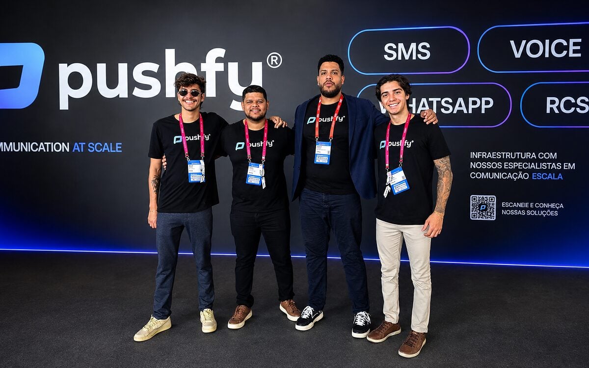 Time da Pushfy no SBC Summit Rio, em frente ao painel da marca